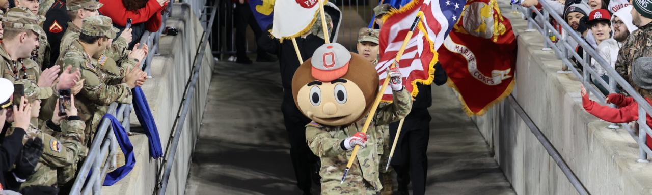 Brutus Buckeye and ROTC cadets run in to Ohio Stadium during a Buckeyes football game.