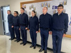 Cadets in their blues lined up against a wall and standing at attention.